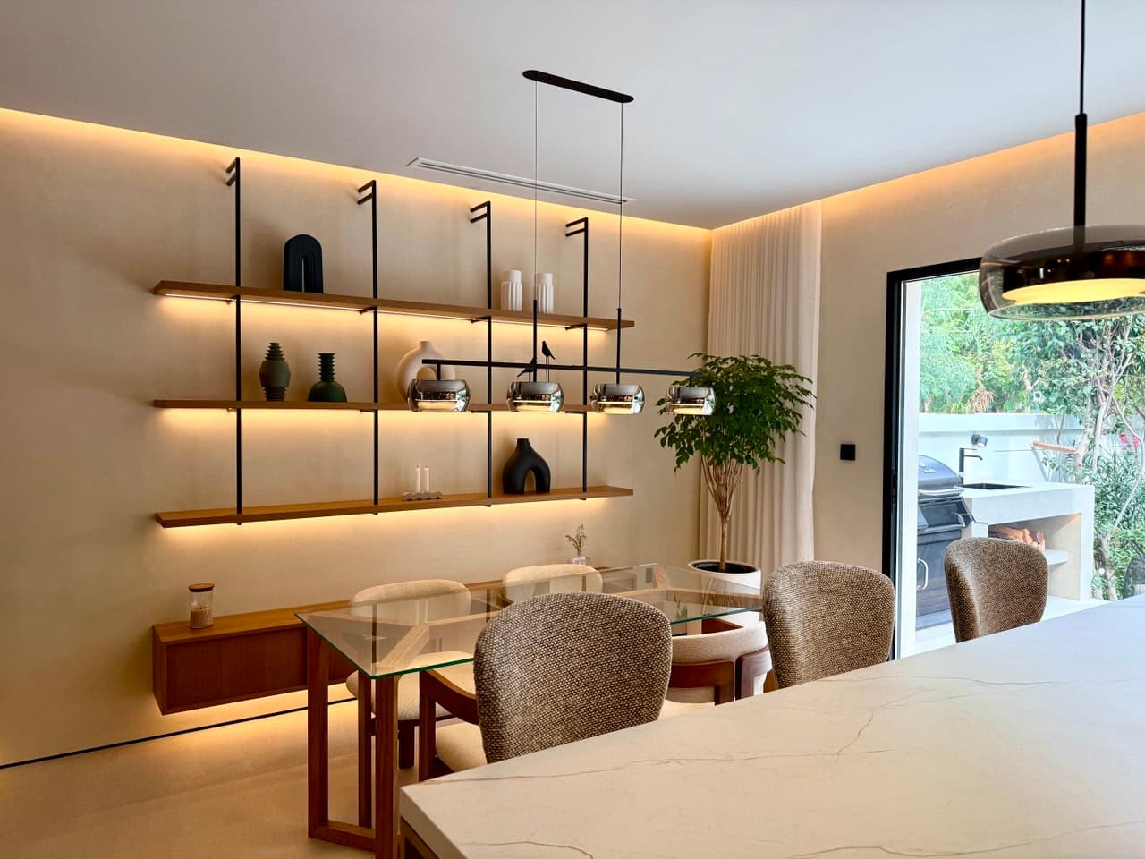 Open-plan villa dining room with bespoke shelving, LED-lit niches and warm joinery — luxury renovation by Concreto Technical Services, Dubai